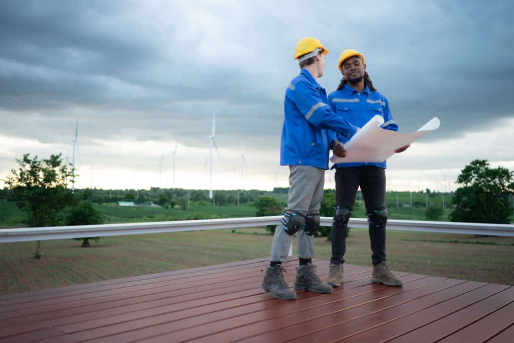 Back view of engineer and technician looking at wind turbines in